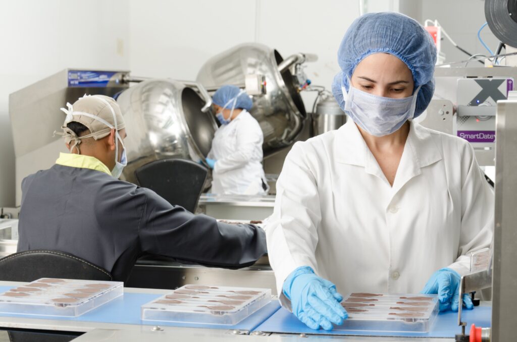 lady-wearing-overall-and-gloves-manufacturing-chocolate-feature-image-for-food-and-beverage-industry-blog