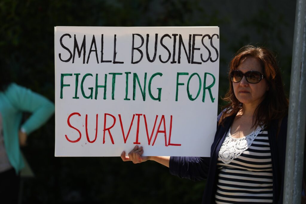 risks for small business blog feature image - lady holding sign saying small business fighting for survival